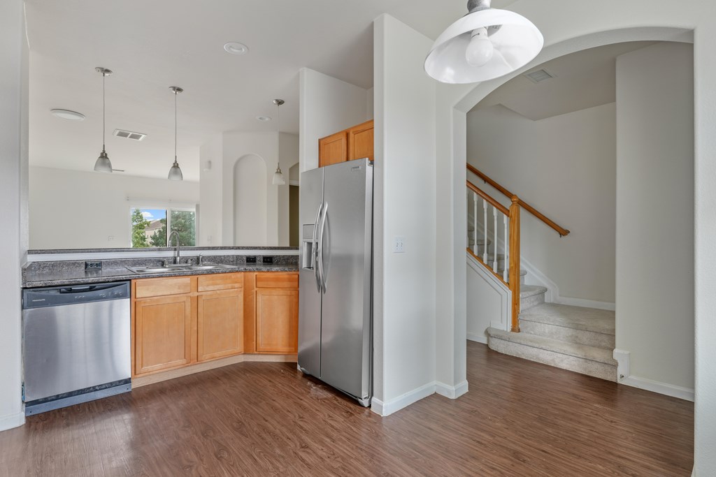 A kitchen with a refrigerator and a stainless steel dishwasher.