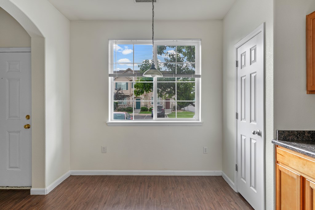 A room with a window showing a view of houses and trees.