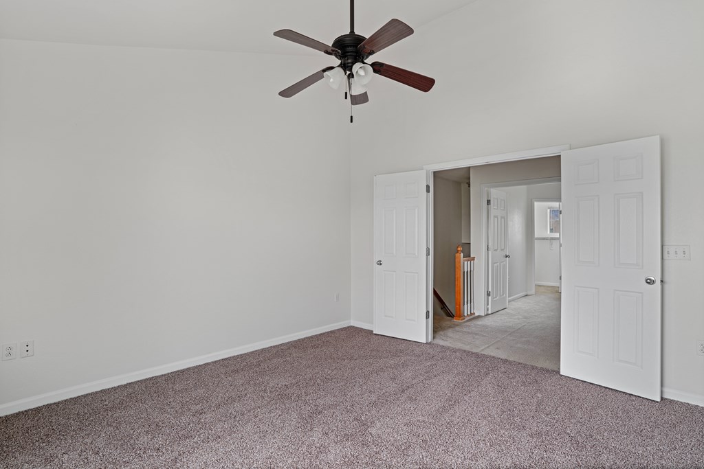 A room with a ceiling fan and carpeted floor.