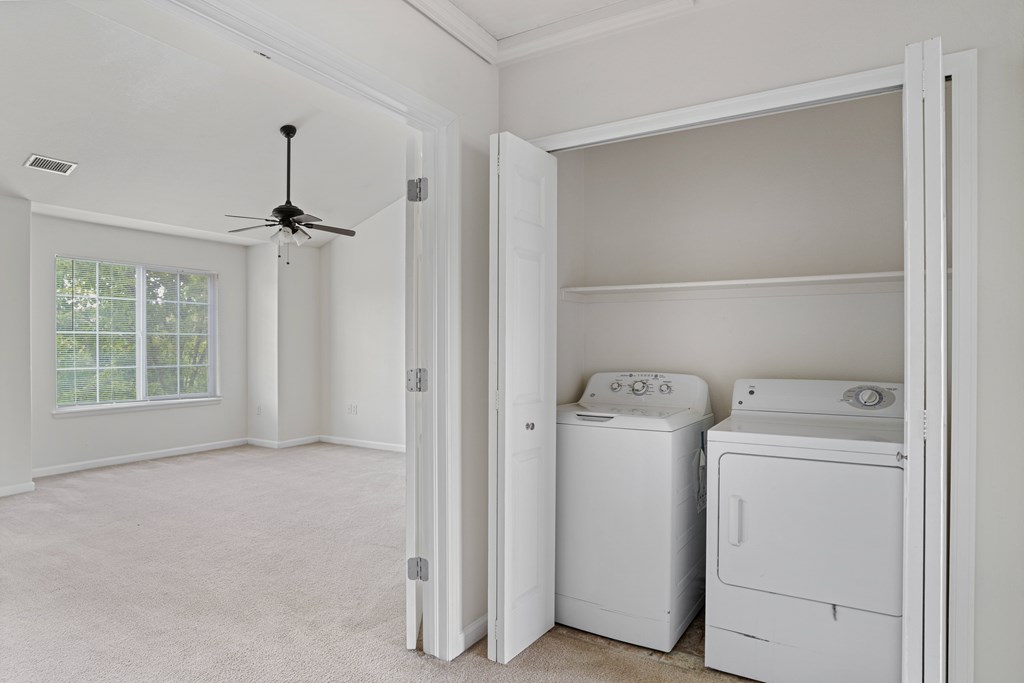 A room with a ceiling fan and two washing machines.