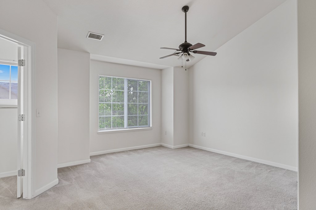 A room with a ceiling fan and a window with blinds.