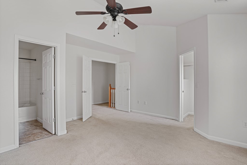 A room with a ceiling fan and carpeted floor.