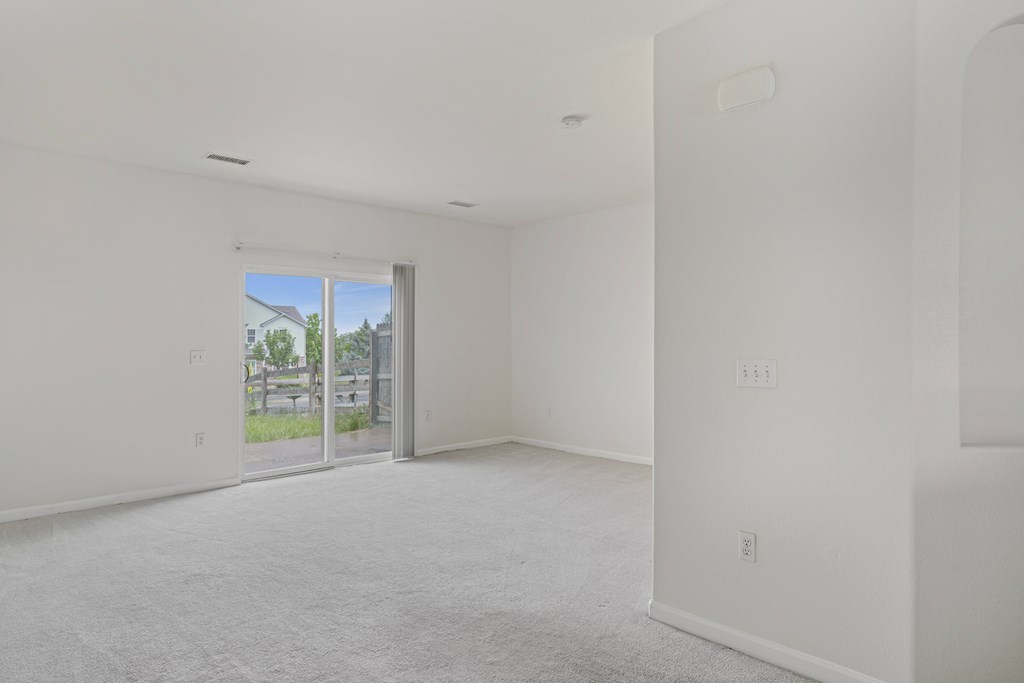 A large empty room with a sliding glass door leading to a patio.