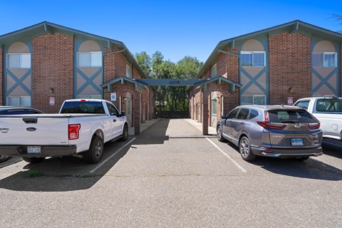 A parking lot with a white truck and a silver car in front of a building with a sign that reads "1037".