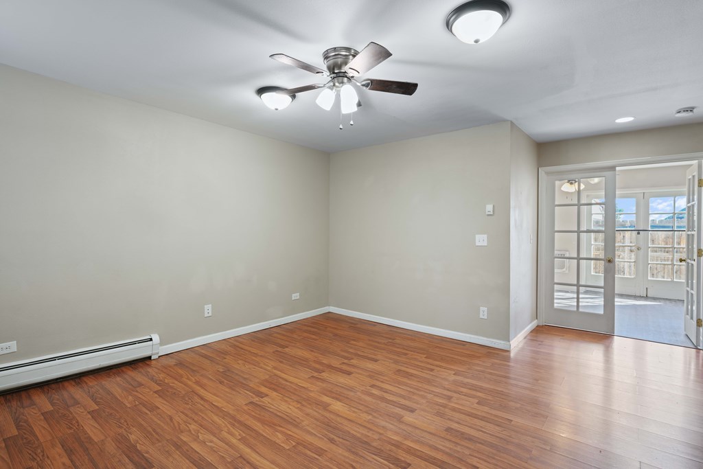 A room with a ceiling fan and wooden flooring.