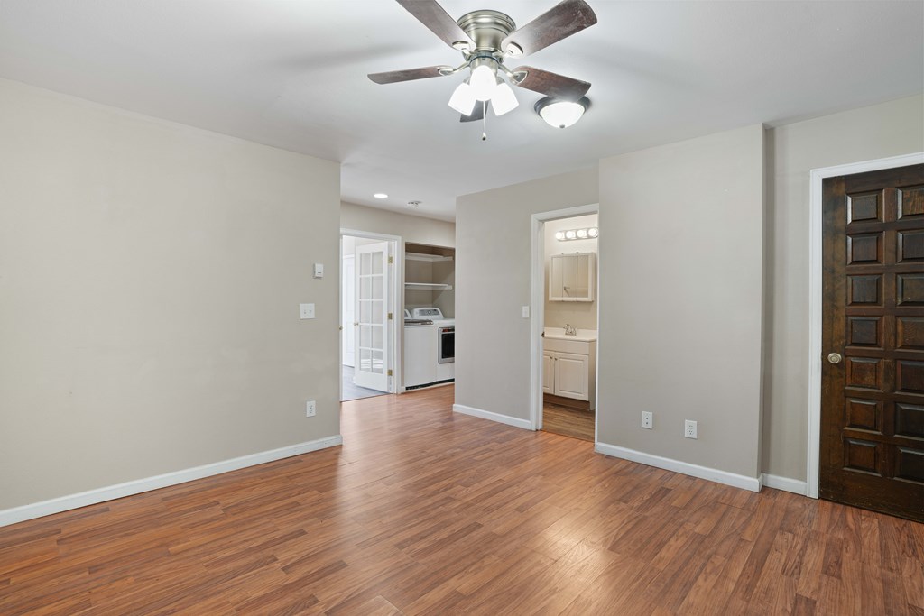 A room with a ceiling fan and wooden floors.