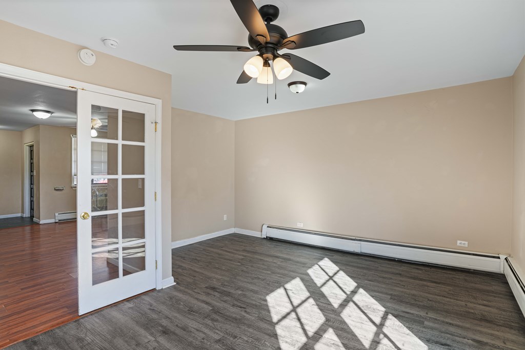 A room with a ceiling fan and a rug on the floor.