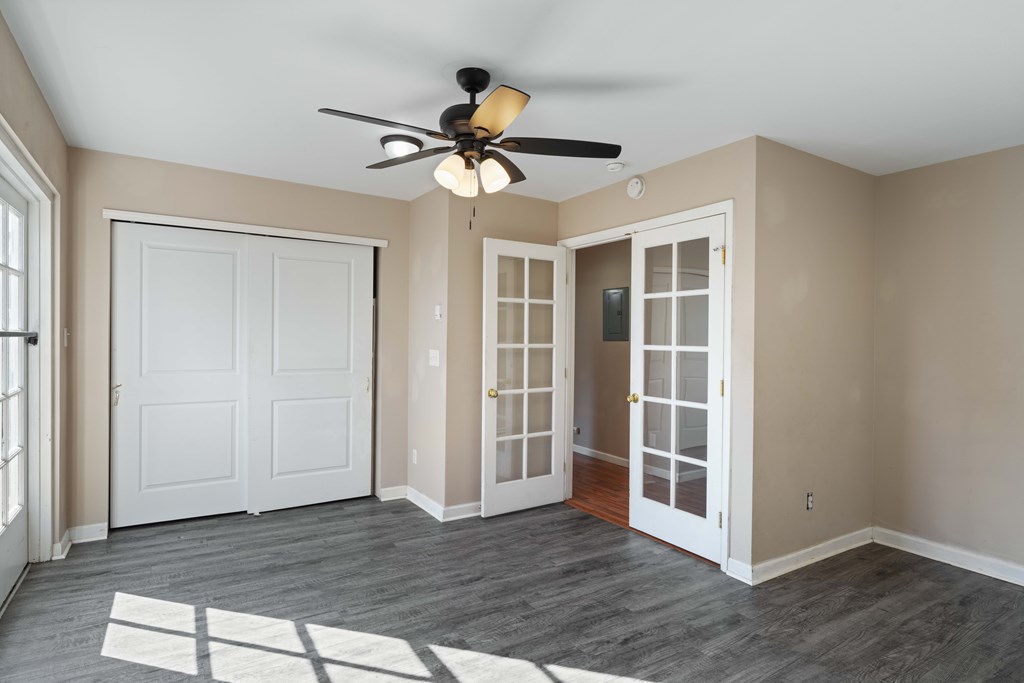 A room with a ceiling fan and a rug on the floor.