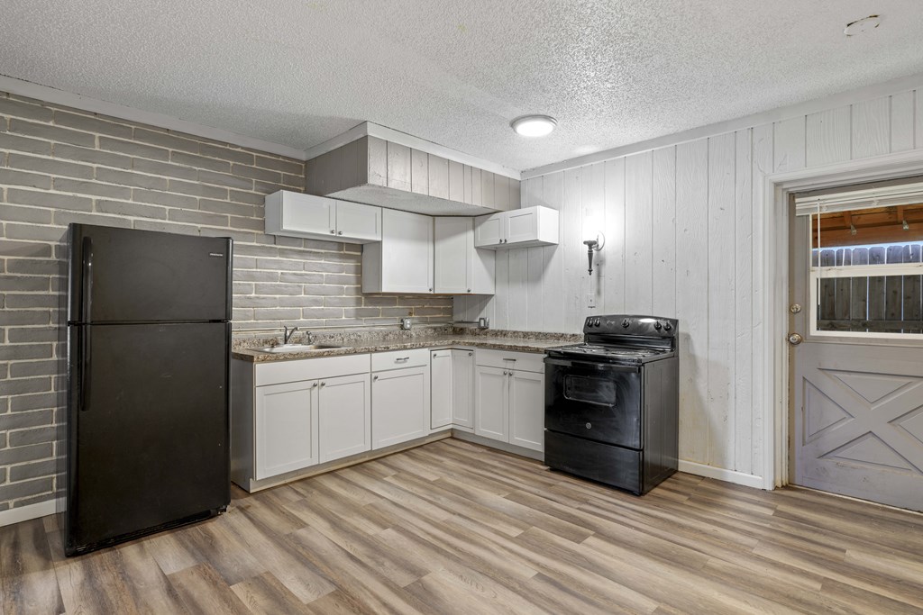 A kitchen with a black refrigerator, black stove, and white cabinets.