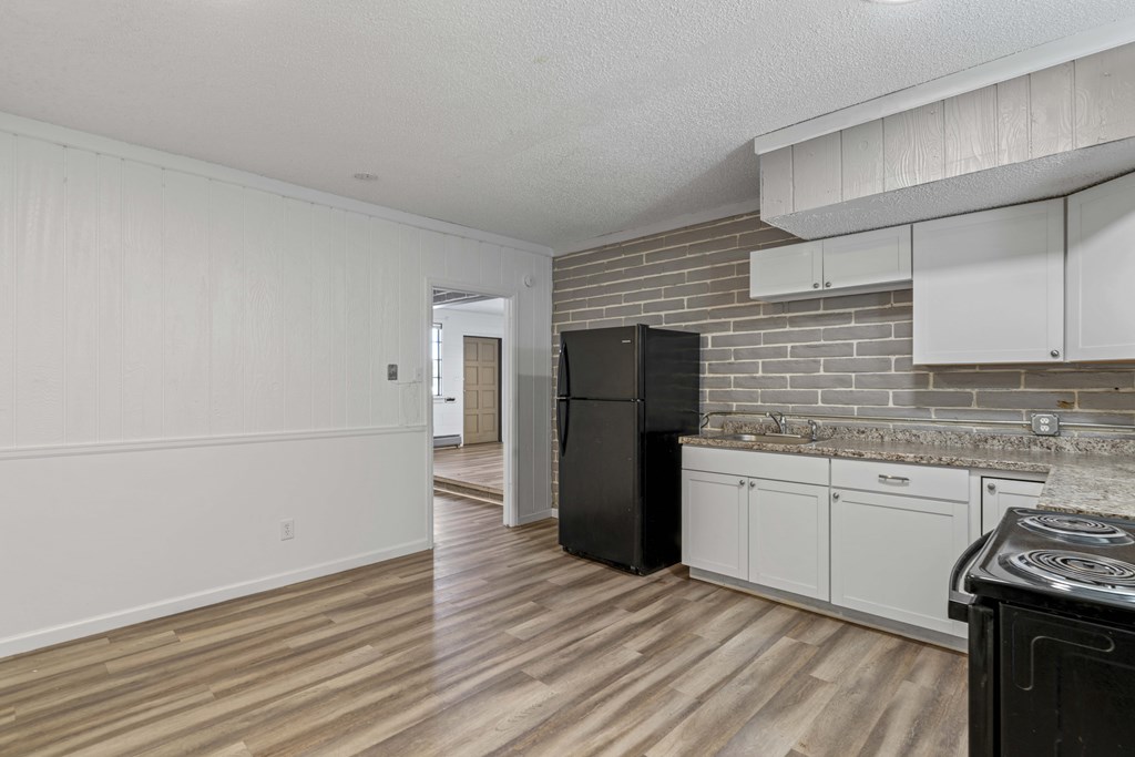 A kitchen with a black fridge and white cabinets.