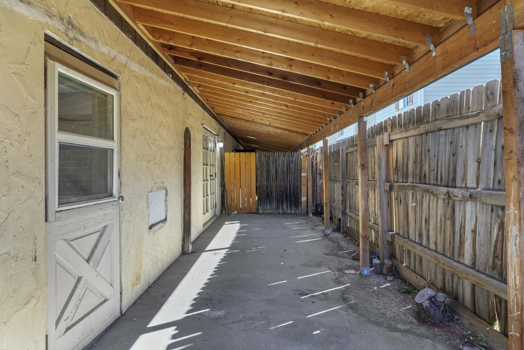 A long covered walkway with a wooden fence on the right side.