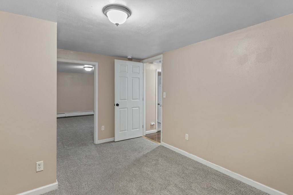 A room with a white door and carpeted floor.
