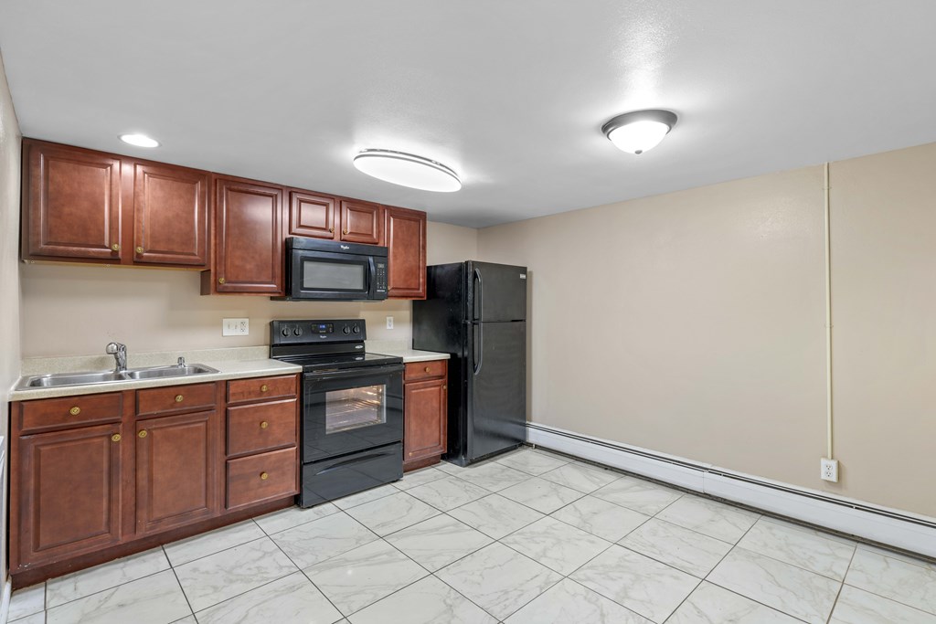 A kitchen with black appliances and brown cabinets.