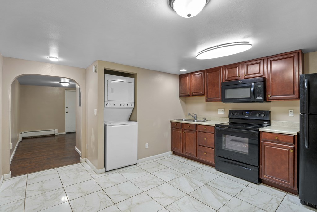 A kitchen with black appliances and brown cabinets.