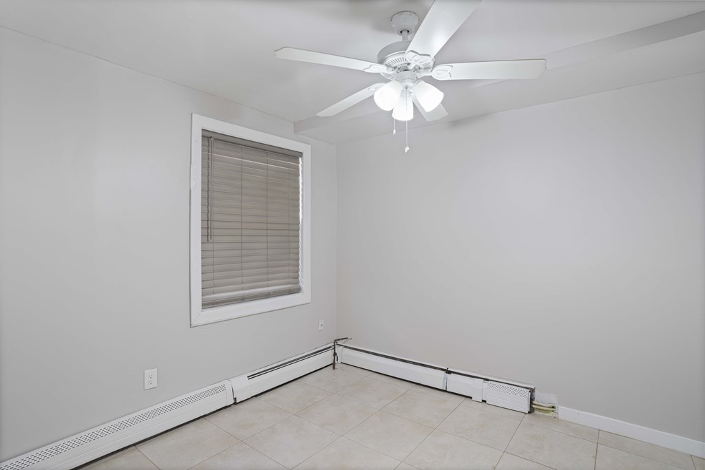 A room with a ceiling fan and a window with blinds.