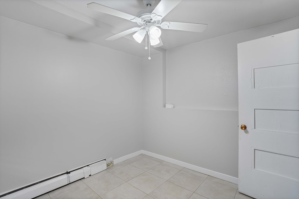 A white room with a ceiling fan and a door.