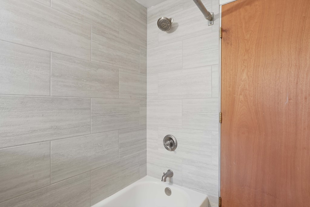 A white bathtub with a silver faucet and a silver shower head.