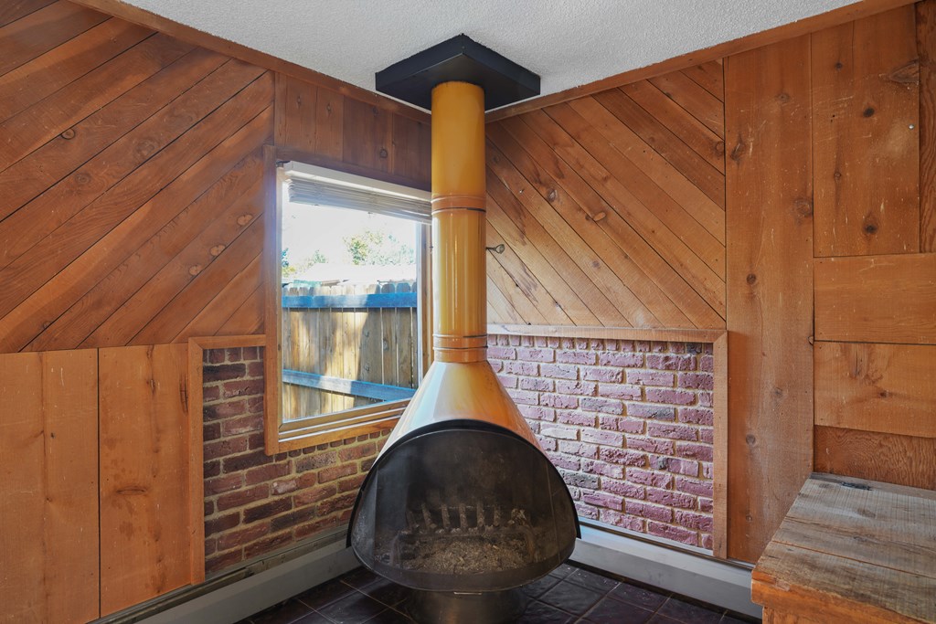 A large pot sits on a brick fireplace in a room with wooden walls.