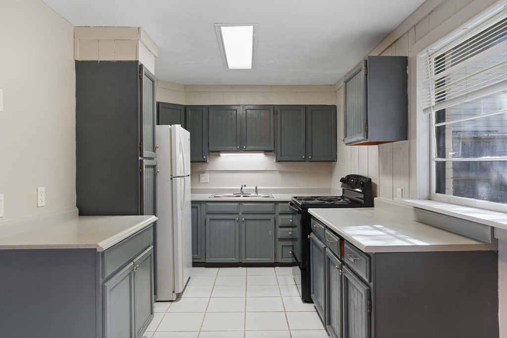 A kitchen with a black refrigerator and cabinets.