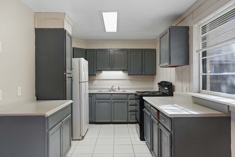 A kitchen with a black refrigerator and cabinets.