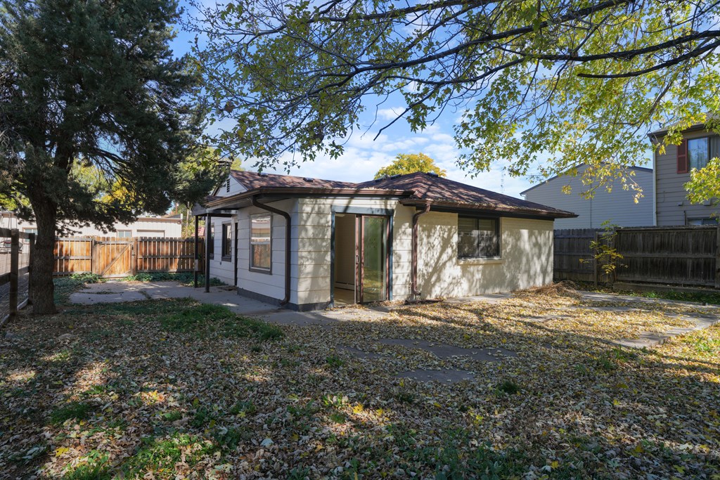 A small house with a brown roof and a fence in front of it.
