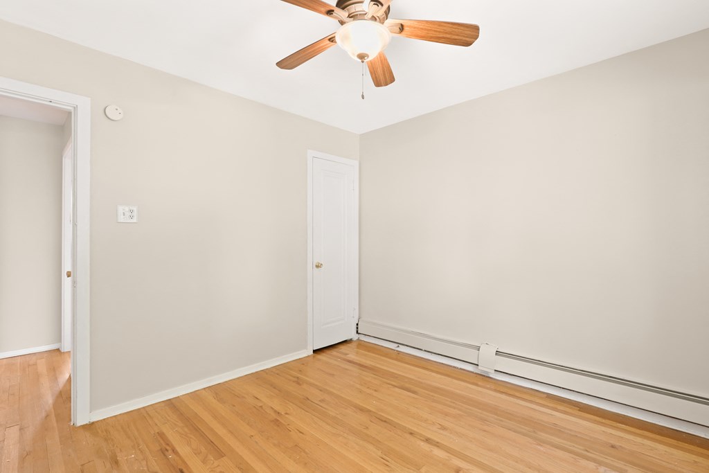 an empty room with wood floors and a ceiling fan