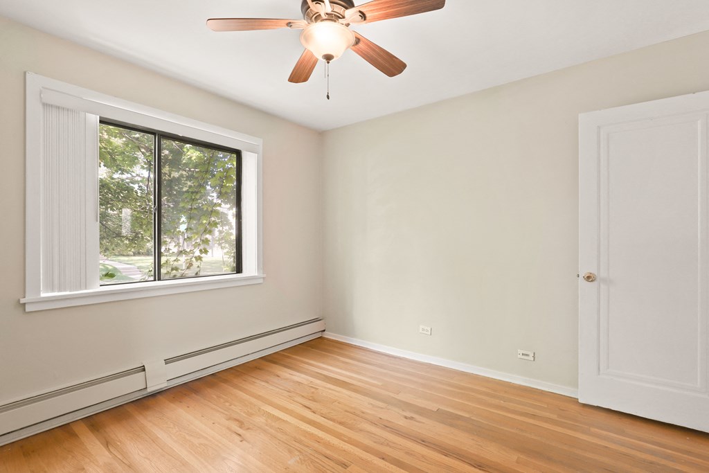 an empty bedroom with a large window and a ceiling fan