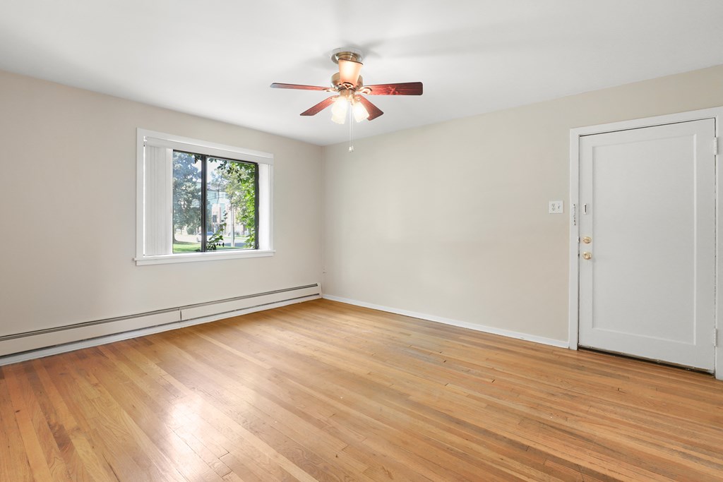 an empty living room with wood floors and a ceiling fan