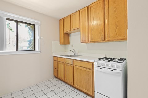 a kitchen with white appliances and wooden cabinets and a window