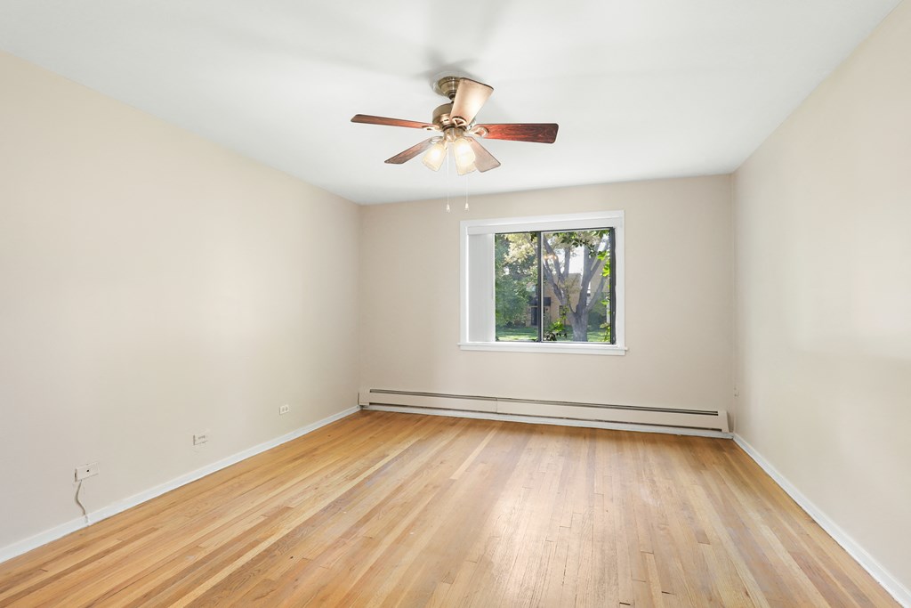an empty room with wood floors and a ceiling fan
