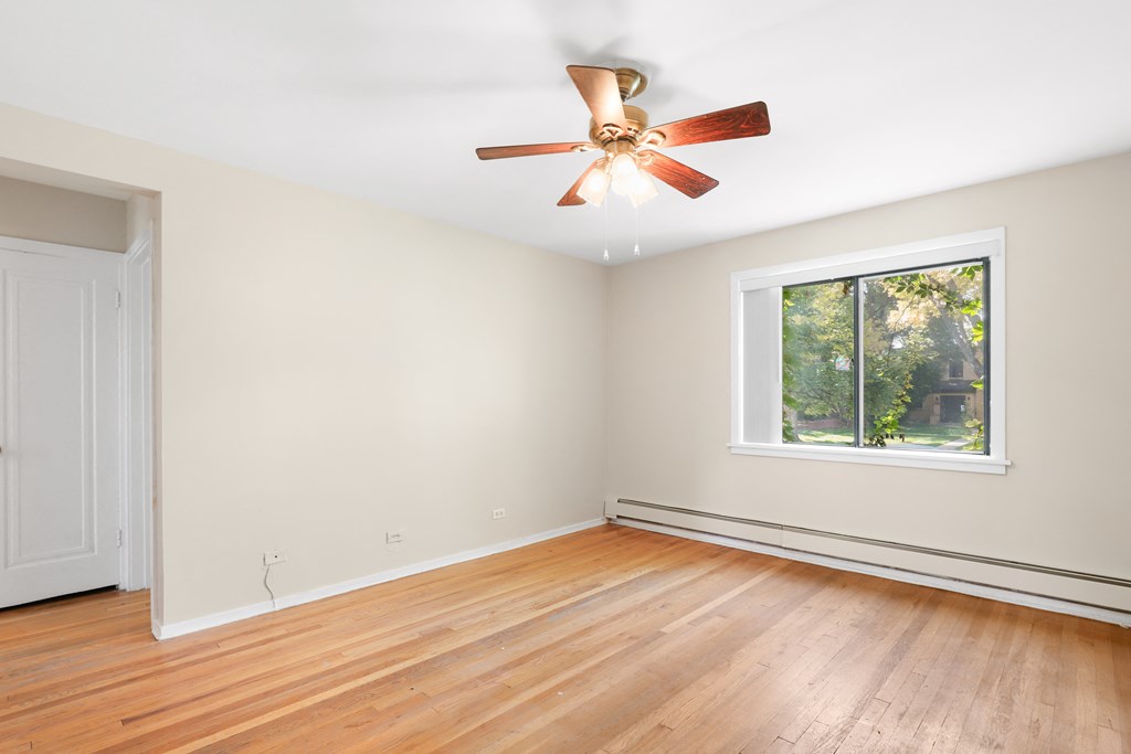 an empty living room with wood floors and a ceiling fan