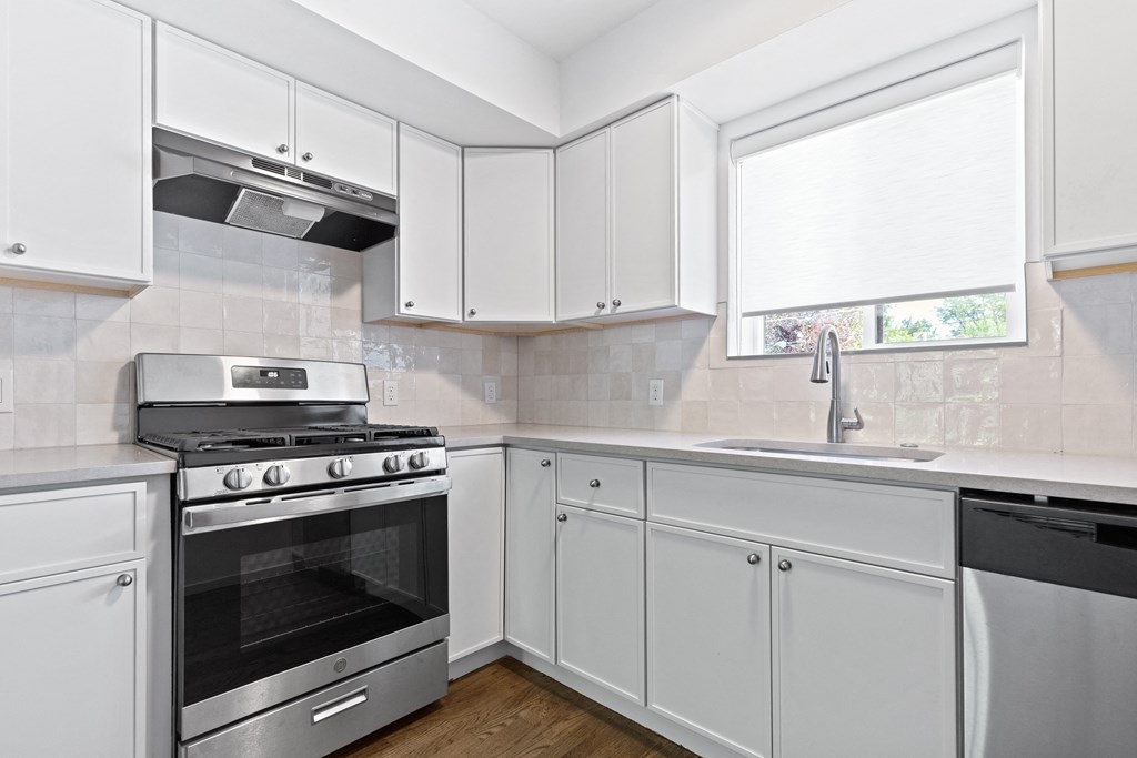 an empty kitchen with white cabinets and stainless steel appliances