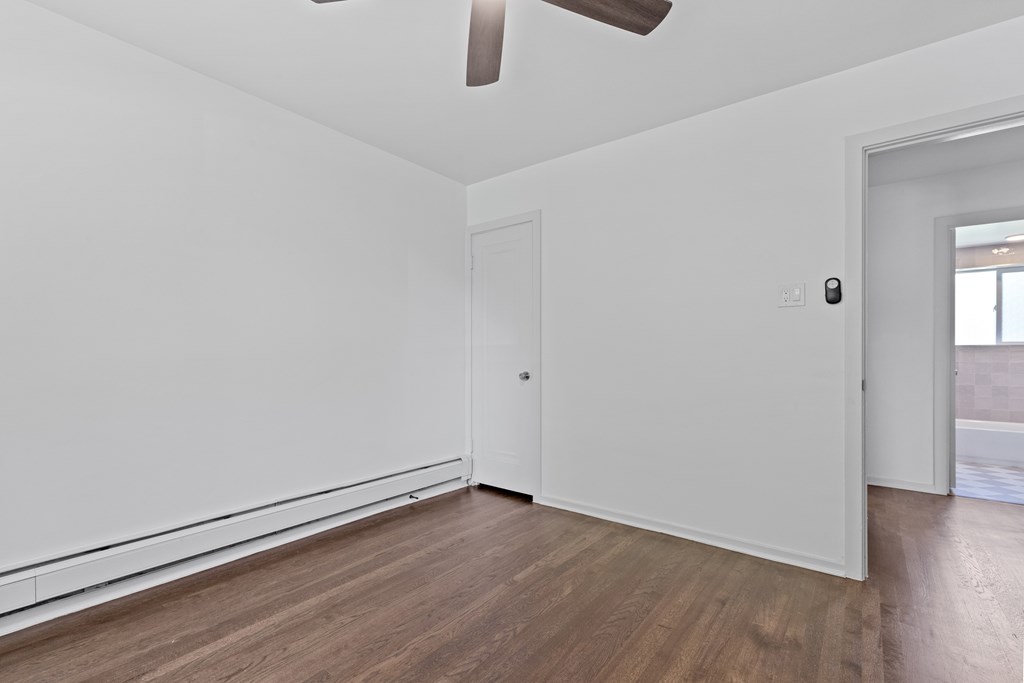 a living room with white walls and wooden floors and a white door