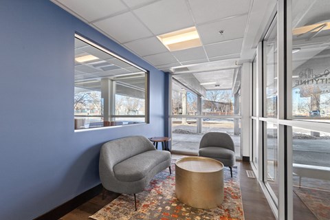 A grey chair sits in a room with a blue wall and a window.