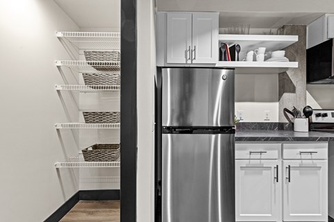 A kitchen with a stainless steel refrigerator and white cabinets.