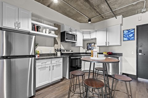 A kitchen with a stainless steel refrigerator and white cabinets.