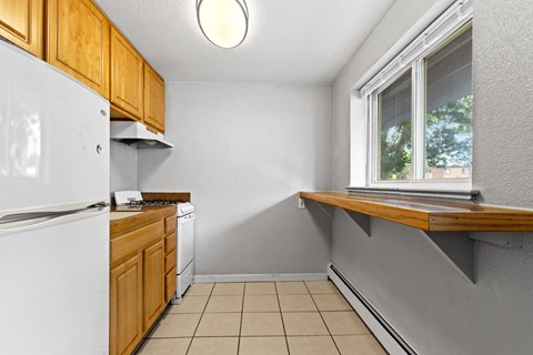 A kitchen with a white refrigerator and wooden cabinets.