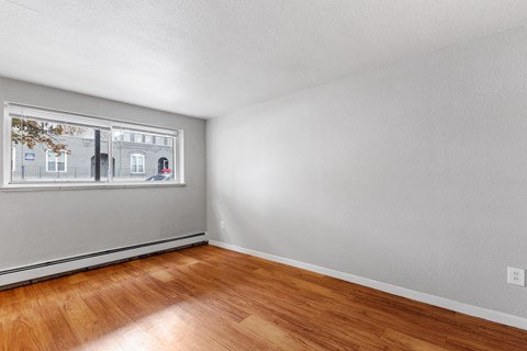 the living room of an apartment with wood floors and a window