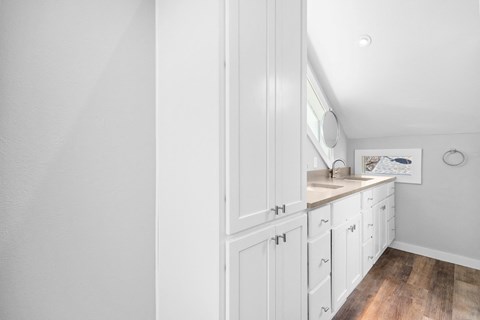 a bathroom with white cabinets and a sink and a mirror