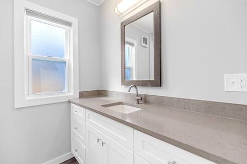 a bathroom with white cabinets and a sink and a mirror
