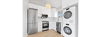 a white kitchen with a washer and dryer and a stainless steel refrigerator