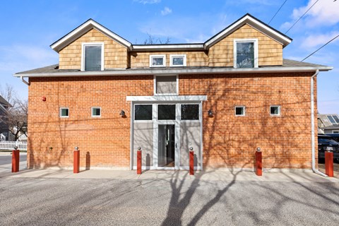 A red brick building with a grey roof and a white door.