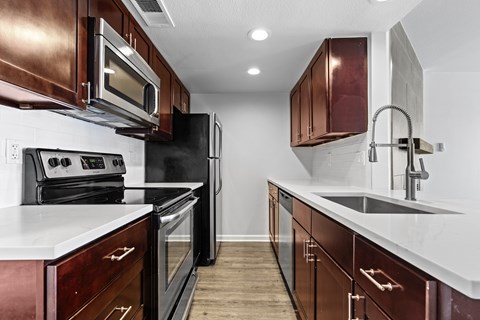 A kitchen with dark wood cabinets and white countertops.