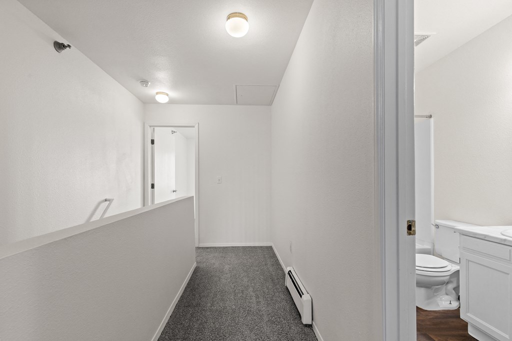 A long, narrow hallway with a carpeted floor and white walls.