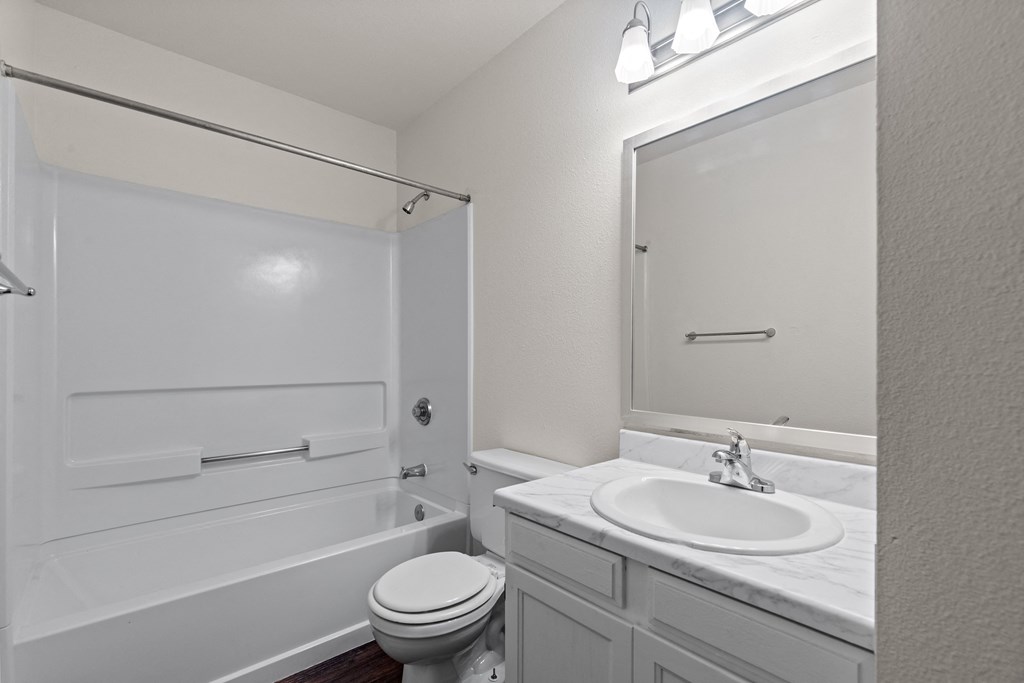 A white bathroom with a toilet, sink, and shower.