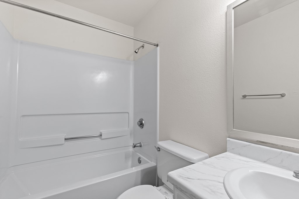 A white bathroom with a toilet, sink, and bathtub.