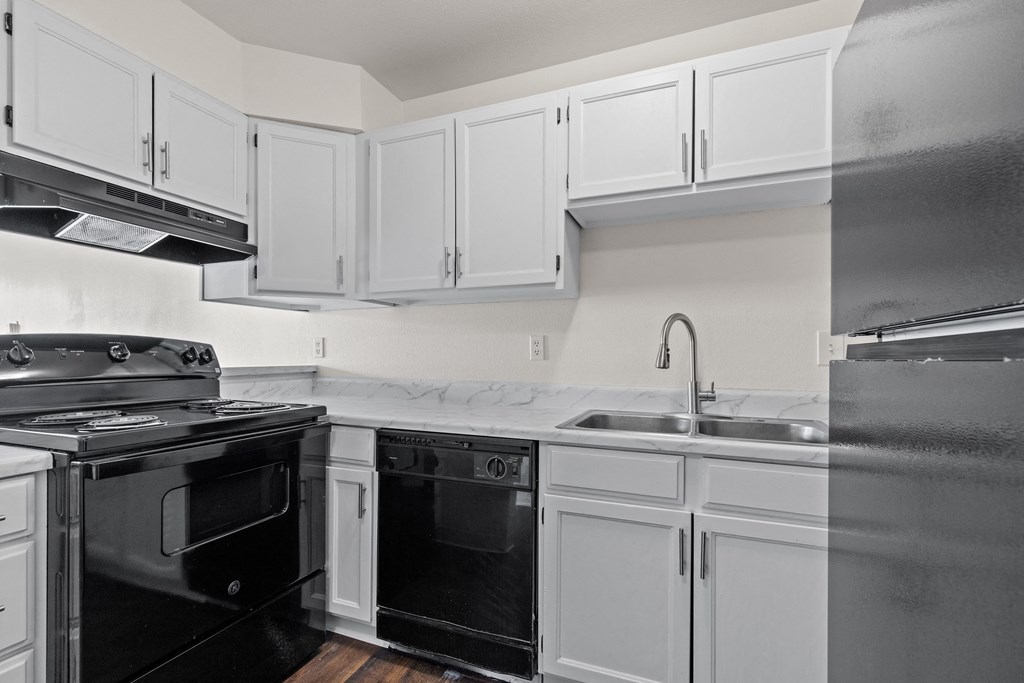 A kitchen with black appliances and white cabinets.