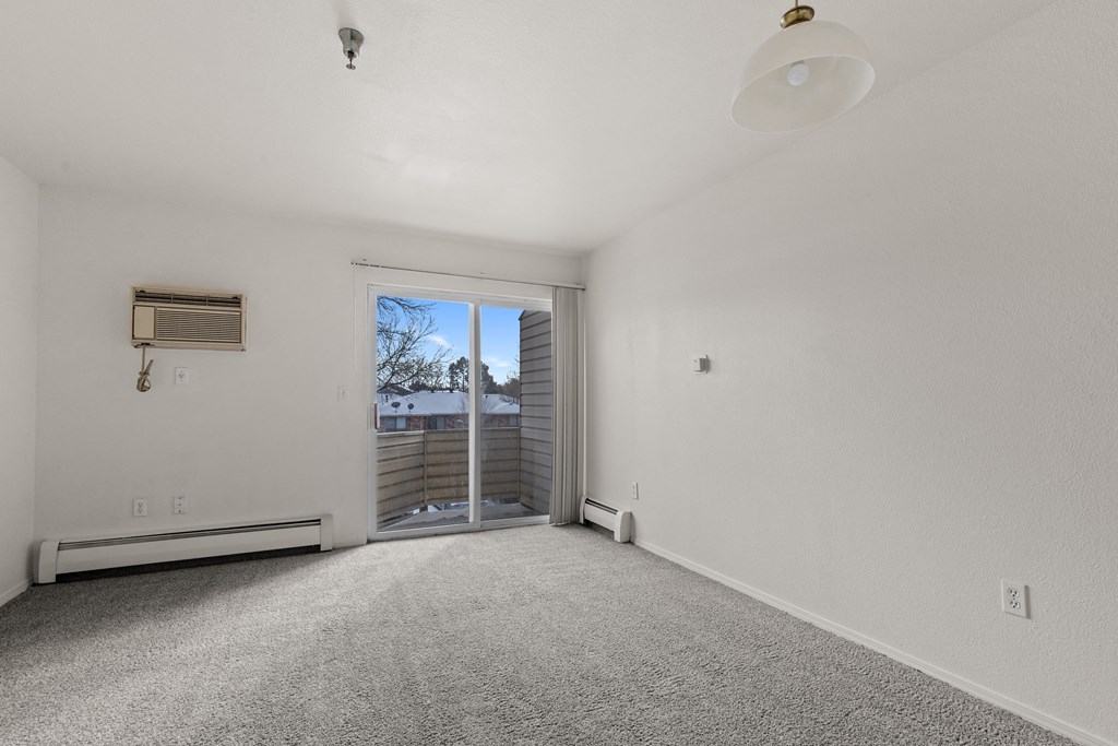 A spacious, empty room with a sliding glass door leading to a backyard.