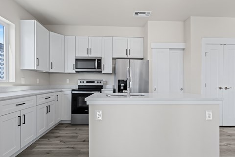 A kitchen with white cabinets and appliances.
