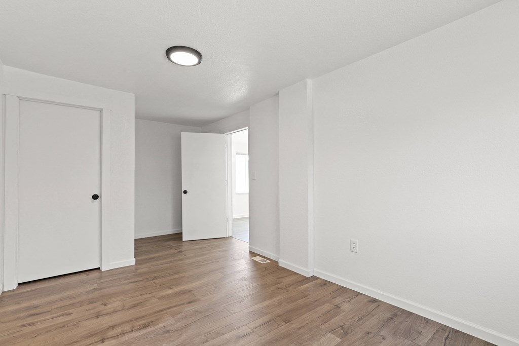 an empty living room with white walls and wood flooring